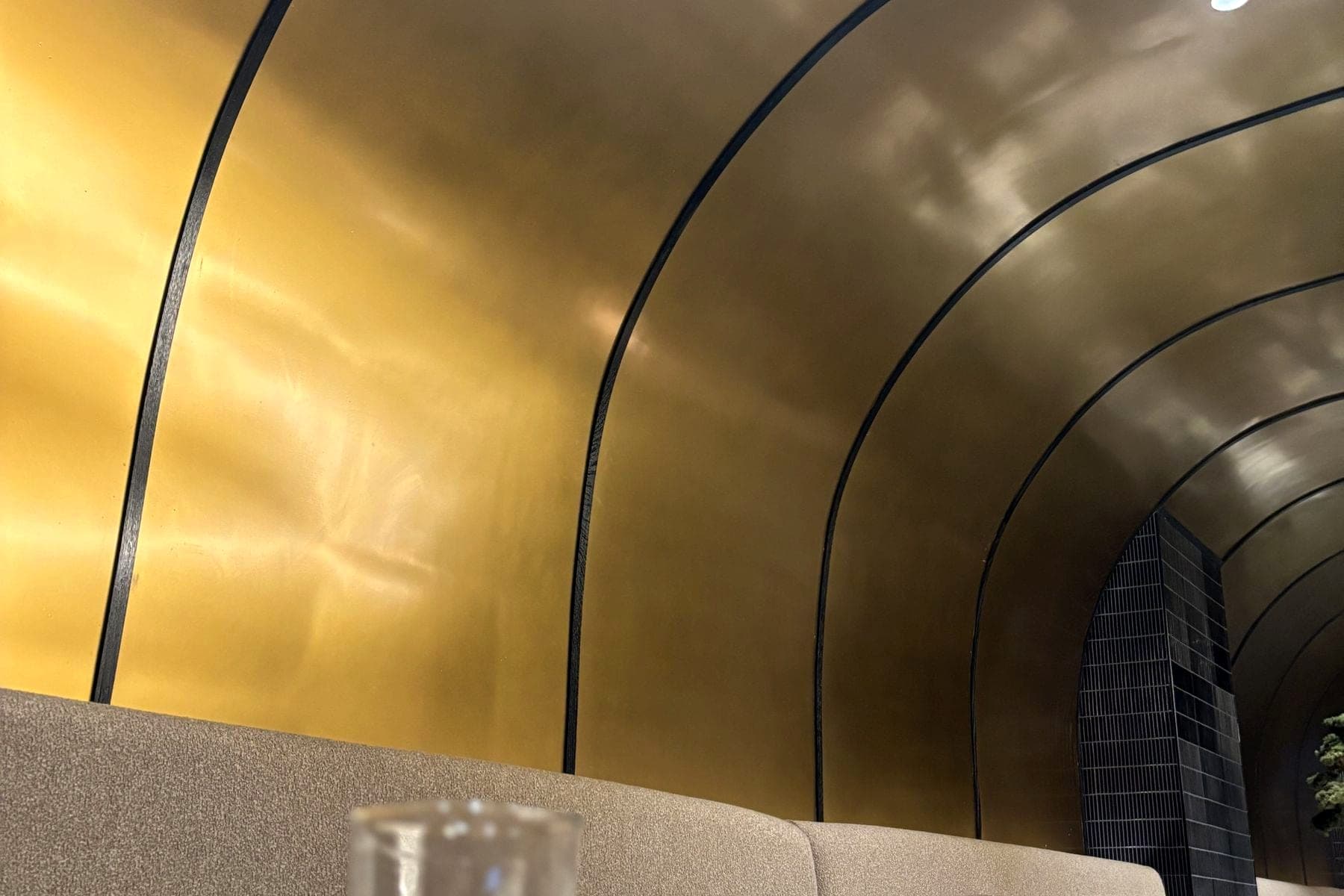 Curved brass ceiling feature over restaurant seating