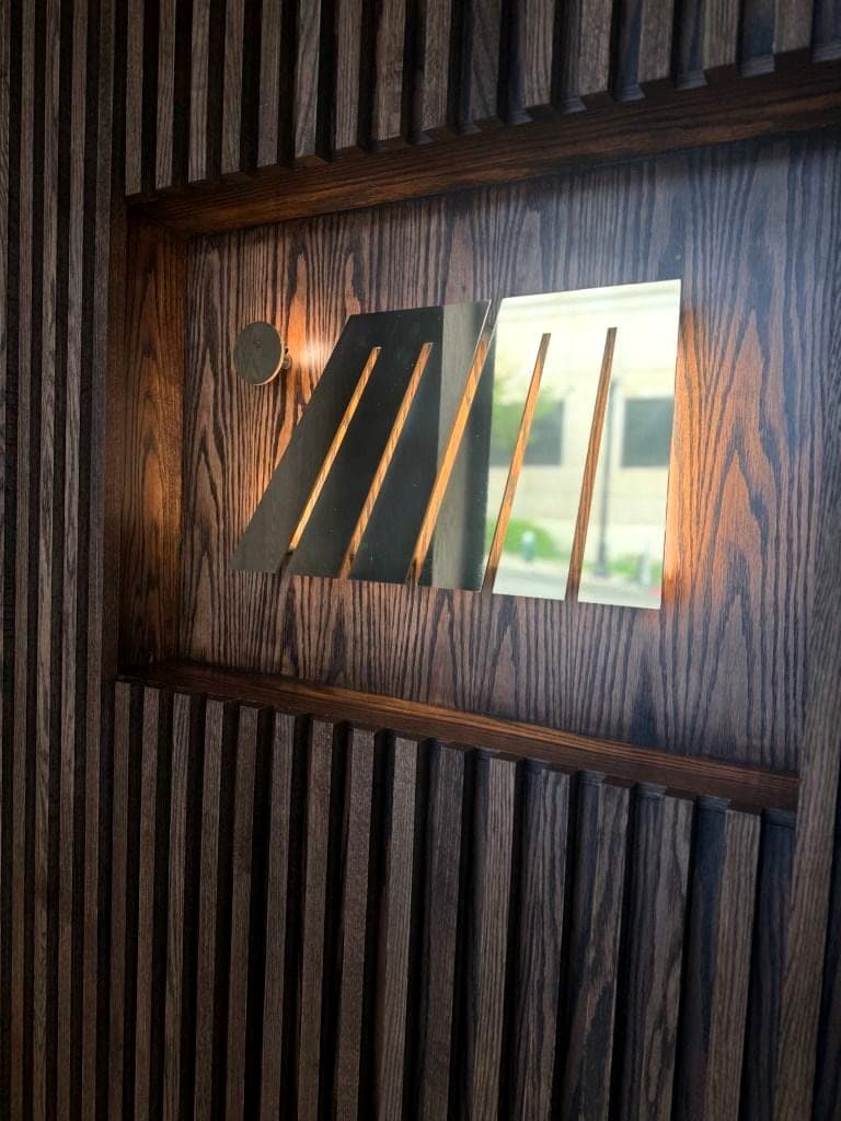 Backlit brass logo sign set into a slat wall